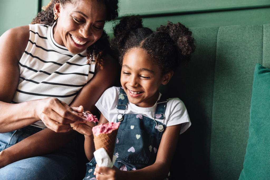 Mother and daughter smiling while sharing ice cream