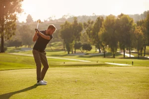 Man swinging golf club with beautiful sunrise